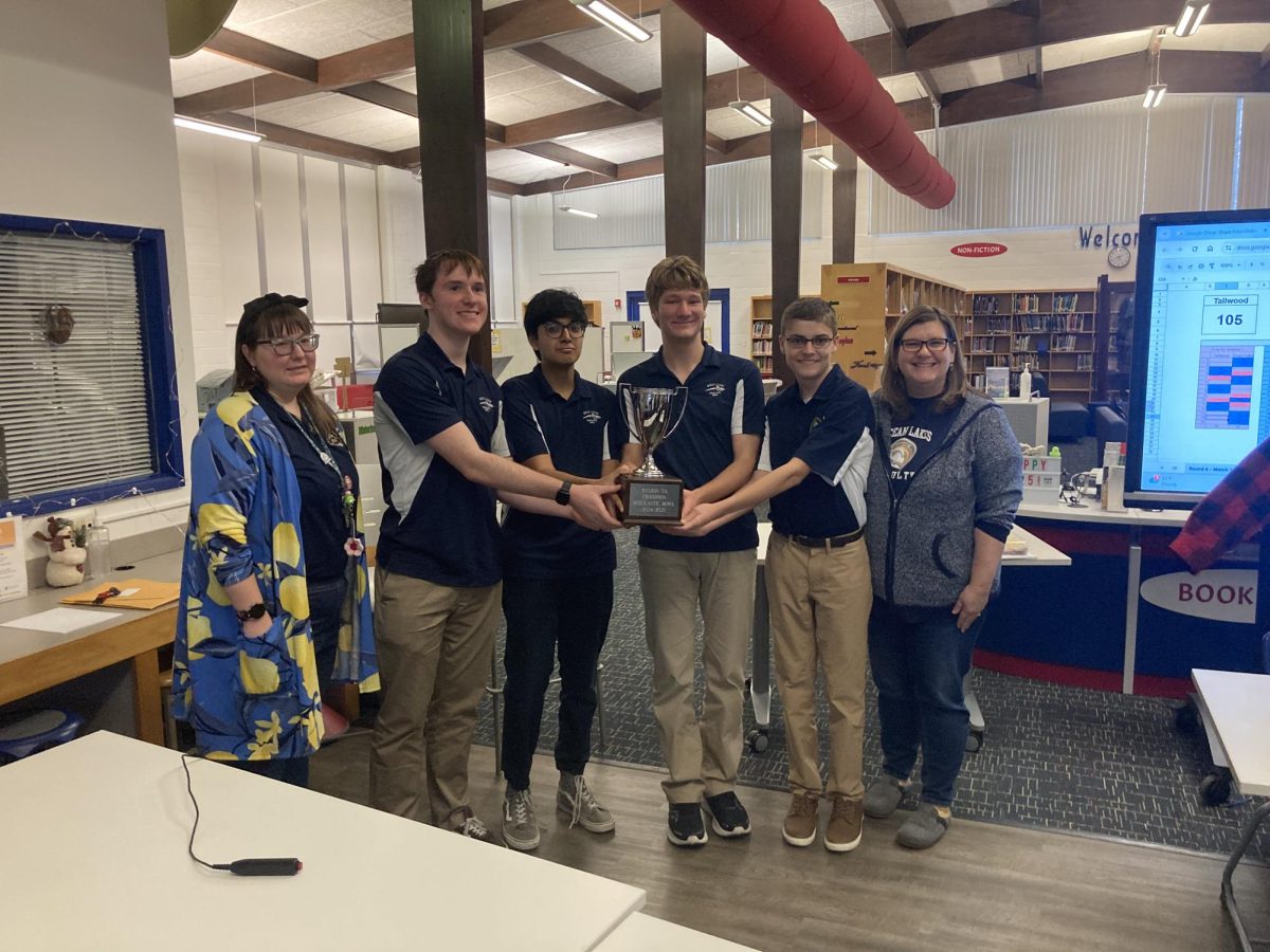 (from left) Miranda Blaser, Clark Smith (11), Kaushik Tatta (12), Jackson Crickard (12), Connor Rakov (9) and Lisa Gibson all stand around their Region 5A trophy at Kempsville High School. The Dolphins won first place and will head to the state tournament in early March. 