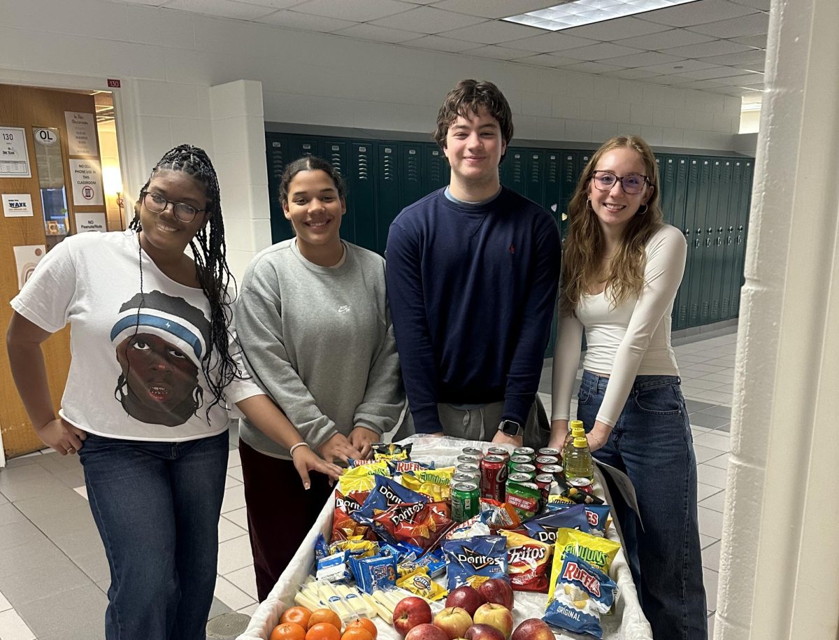 From left to right: seniors Tajiyah Manual, Marlie Smith, Thomas Dillard and junior Anna Daubenspeck hand out breakfast to teachers with the snack cart. Morning breakfast comes around on the first day of the new semester to thank teachers for being outstanding. Photo taken by Fara Wiles.