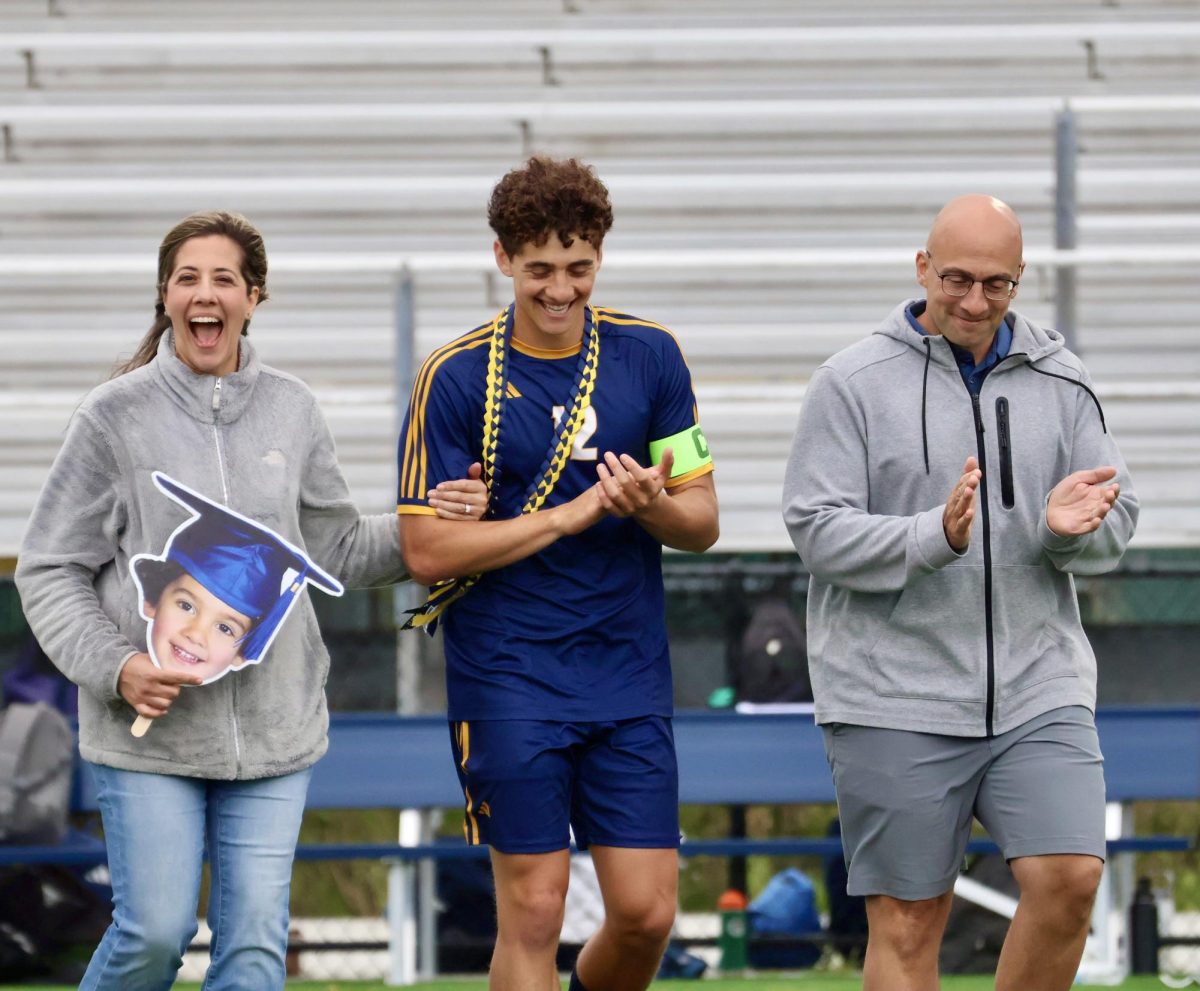 Senior Anthony Liberatore walks alongside his parents during the senior night ceremony on May 21, 2025, at Ocean Lakes High School. Anthony is a captain for the boys team and scored against Granby, heavily assisting in the shut-out for the Dolphins. Photo used with permission from Amanda Marrone. 