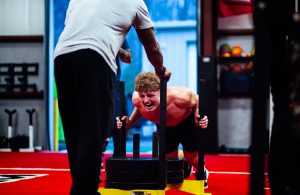 Photo captures linebacker Taylor Vogel doing sled pushes while TNDO trainer and gym owner Giavanni Ruffin pushes back. This photo was taken on March 12, 2025 during the Dolphin’s football workout. Photo used with permission by Giovanni Ruffin.