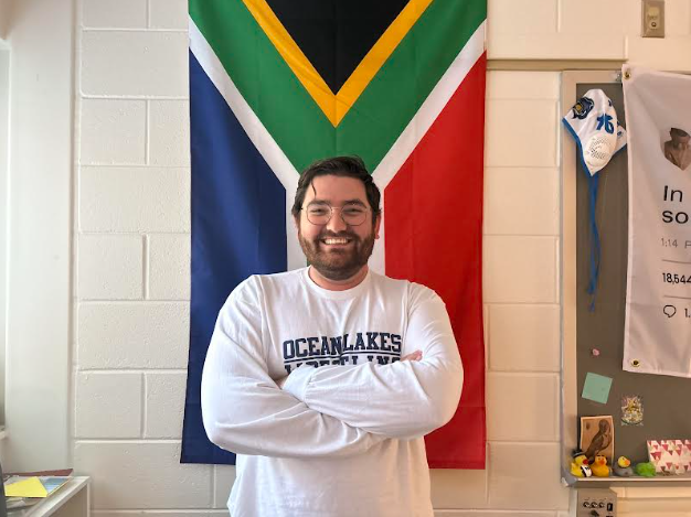 Jared Swift stands in front of his South African flag located behind his desk. Swift's classroom is in room 155 in the history hallway. Photo taken on April 9, 2025.