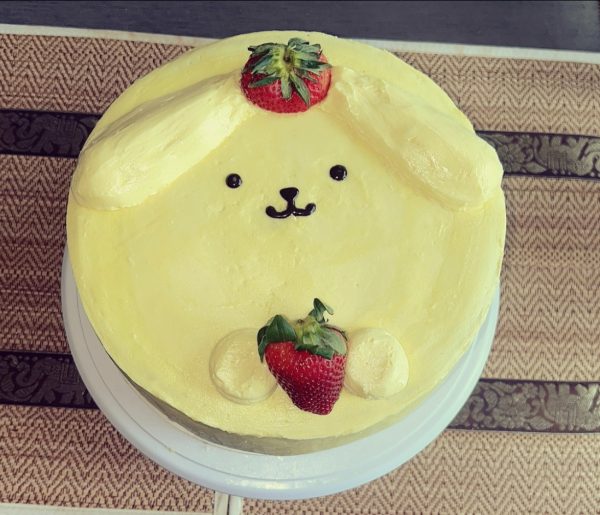 A cake meant to resemble the Sanrio character “Pompurin” with strawberries embedded in it. This cake was made on April 26, 2025, before Arkilis officially started the business. This photo was taken by Arkilis Rodriguez-Coss and is used with her permission.