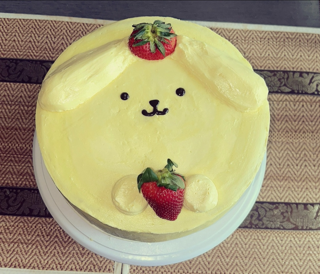 A cake meant to resemble the Sanrio character “Pompurin” with strawberries embedded in it. This cake was made on April 26, 2025, before Arkilis officially started the business. This photo was taken by Arkilis Rodriguez-Coss and is used with her permission.