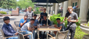 Pictured from left to right: sophomores Juno Paguiligan, Eeshan Desai, Marshall Shoemaker, Tulga Rentsendorj, Chris Litto, Stone Wagner, Tyler Rafalski, Vihaan Shah and Brayden Knowles sit outside for lunch on May 16, 2025 at the Chrysler Museum in Norfolk, Virginia. The students went on an AP Euro field trip to observe various pieces of artwork. Photo courtesy of Sam Pili. 