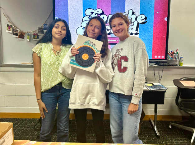 From left to right: sophomore Nidhi Aleti, junior Emilia Florentino, and senior Lauren Rekov showcasing this year's yearbook. They were distributing them in Ashley Adams room in 145 during one lunch.
