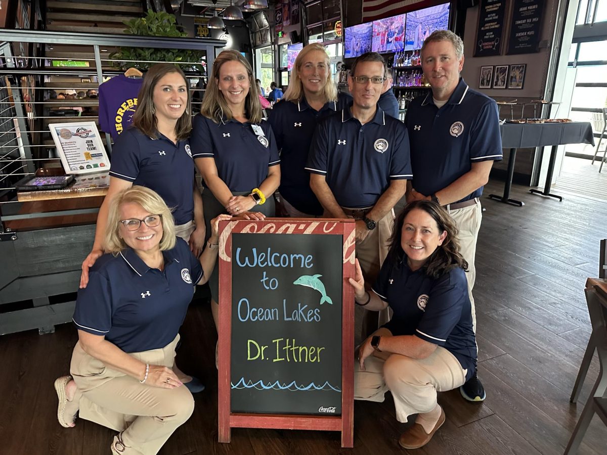 The OLHS administrative team poses around a sign at Shorebreak Pizza. From left to right: Dorothy Neal, Jenna Filipowicz, Dr. Leslie Ittner, Michele Clark, James Imbriale, Michael King, and Dr. Carrie Gantt. 