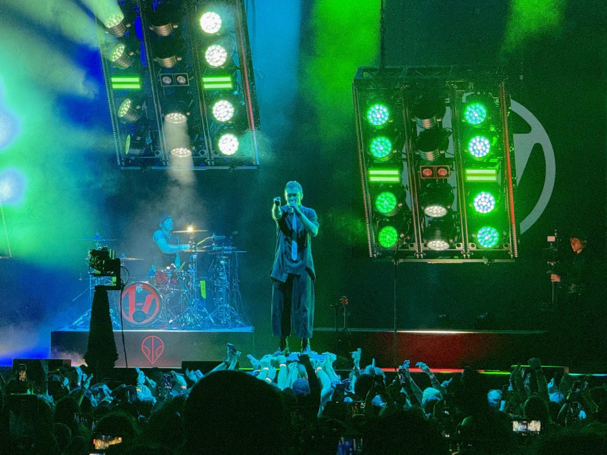 Twenty One Pilots lead singer and guitarist Tyler Joseph performs “Lane Boy” on Oct. 7th at the Veterans Home Loans Amphitheater at Virginia Beach. Joseph stands on a platform hand-held by fans in the crowd.  
