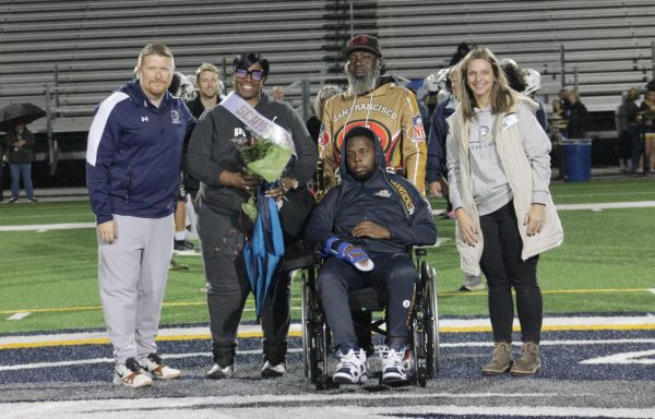 Jamarie Sanders is escorted by his parents Annita Patterson and Elmomar Sanders down the 50-yard line to gather with head coach James Yeager and Principal Dr. Leslie Ittner for Senior Night. Senior Night was celebrated on Nov. 7, 2025, at Ocean Lakes High School.