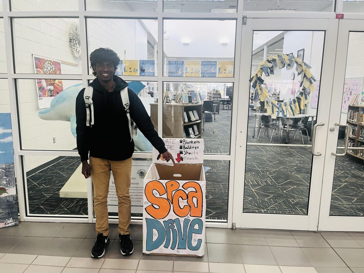 Sophomore Nathen Varghese smiles in front of the donation box for a Pet Drive event taking place from Jan. 5-30. The Pet Drive is sponsored by the SPCA. 
