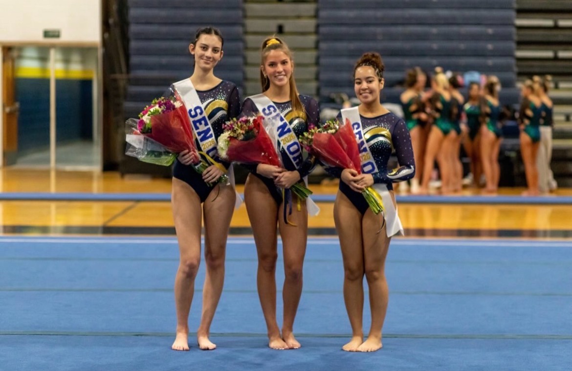 Pictured left to right: Seniors Kathrine Elliot, Charley Snellinger and Yasmin Williams accept flowers and smile for parents and friends on the mat at Senior Night.
Senior Night took place on Dec. 4, 2025 at Ocean Lakes High School. Picture used with permission of Ted Calise.
