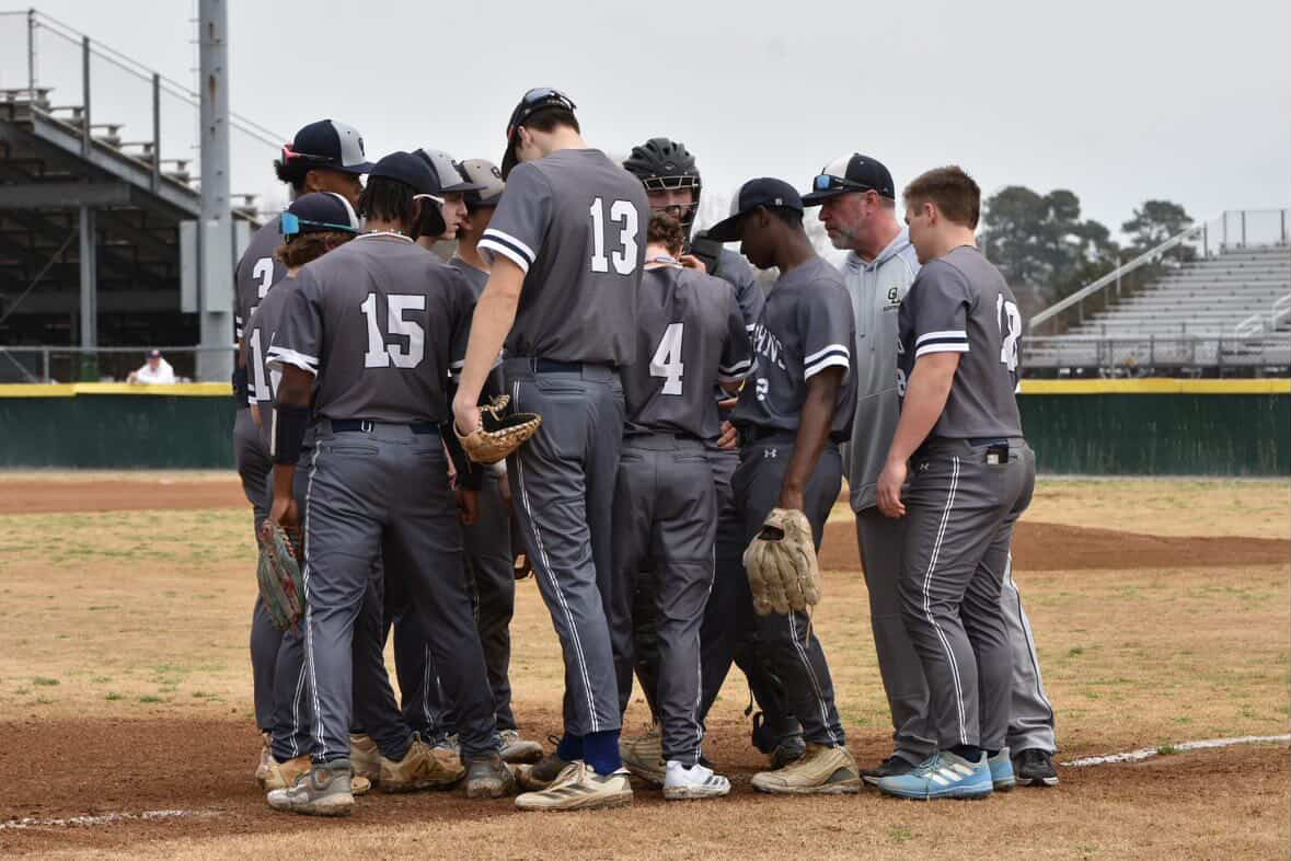 The team huddles around assistant coach AJ Buckland at  third base before their scrimmage on March 7, 2026, against 
Grassfield. The team won the game 3-2. Photo used with permission from Katie Hostetler.
