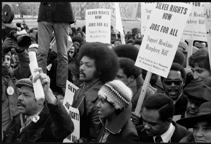 Jesse Jackson marches among protestors in Washington D.C. on April 26, 1975. The protestors marched from the capitol building, protesting unemployment. Photo by Thomas O’Halloran (accessed from Creative Commons). 