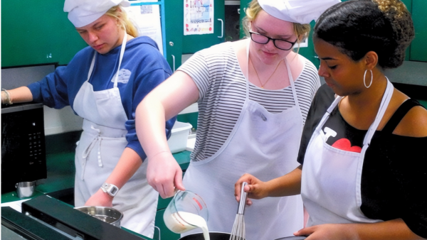 Pictured left to right: Sophomores Payton Ferguson, Kelcie Husbeck, and Tiana Ventura create a roux for mac and cheese. Kelcie poured the milk, while Tiana stirred the roux, and Payton prepped the cheese for the dish for the Edmarc Foundation.