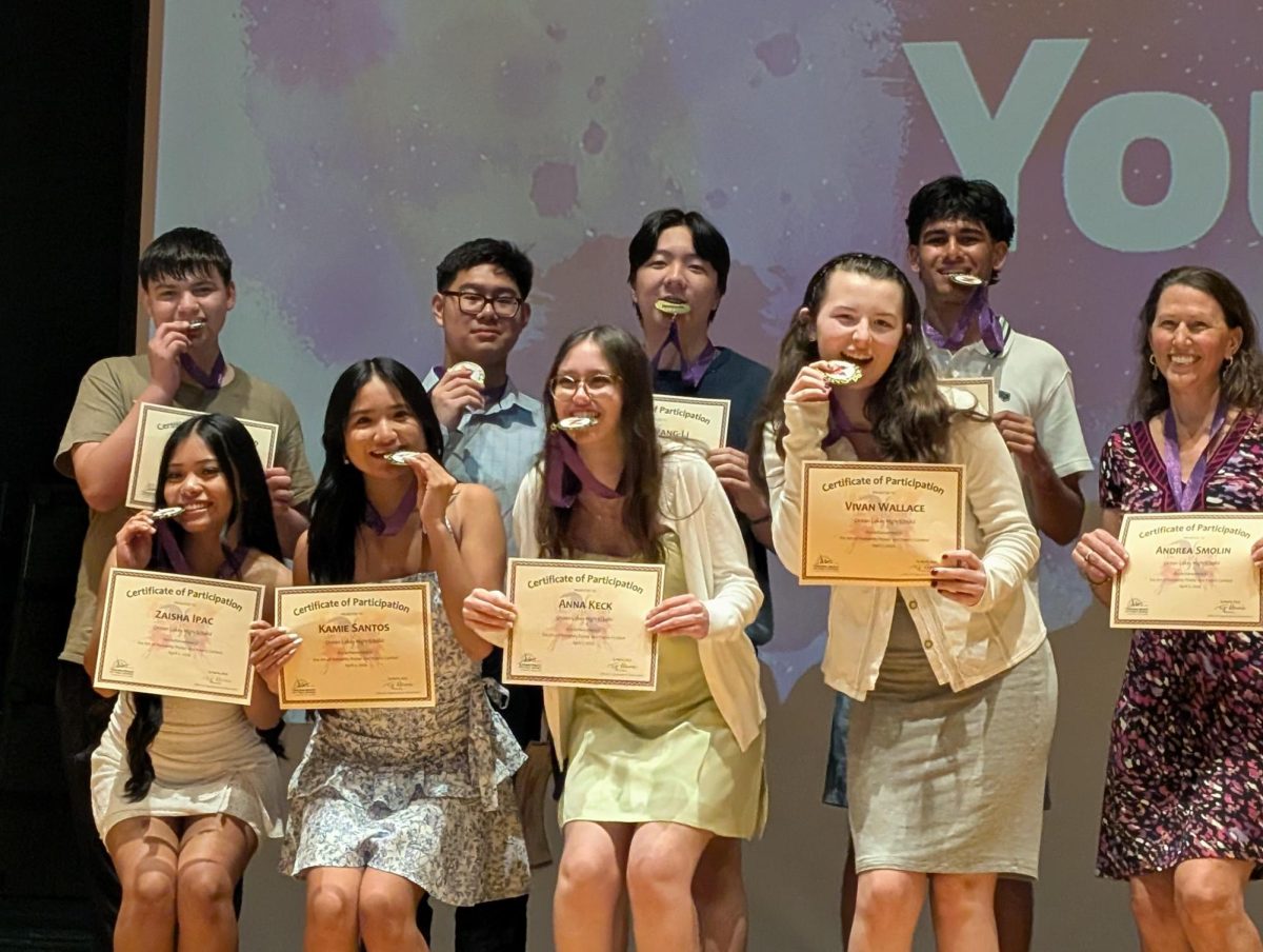 Sophomore Zander Hubbard, juniors Calvin Hartono, Evan Wang-Li, Vihaan Shah, Zaisha Ipac, Kamie Santos, Anna Keck, sophomore Vivian Wallace, and teacher Andrea Smolin display their awards while biting their medals. This picture was taken at the award ceremony at Tallwood High School on Apr. 2.