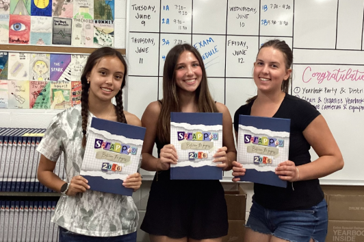 Pictured left to right, sophomore Sloane Phaneuf, sophomore Camryn Early and junior Charlotte Strunk smile with their yearbooks in room 145 on May 20 during One Lunch. The three became friends in yearbook class this school year.