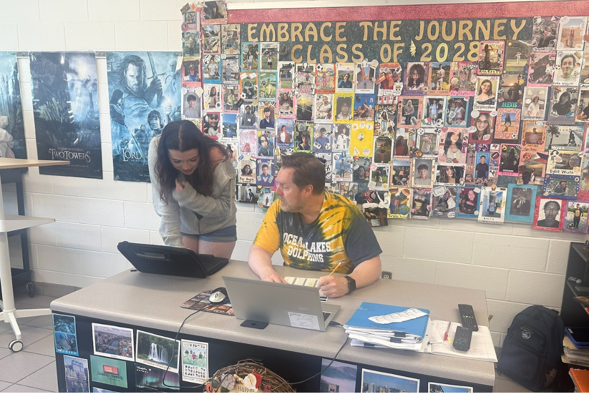English teacher Don Kroeller helps sophomore Aubrie Ballweg on her Joy Luck Club Heritage Project in Room 123 during Block 4B. The Joy Luck Club Heritage Project requires students to analyze the novel's themes and share their own family history.