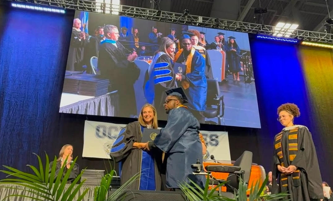 Accompanied by English teacher Sarah Burford, senior Jamarie Sanders stood to receive his high school diploma from Principal Dr. Leslie Ittner at the Virginia Beach Convention Center on June 10. Photo courtesy of Virginia Beach City Public Schools.